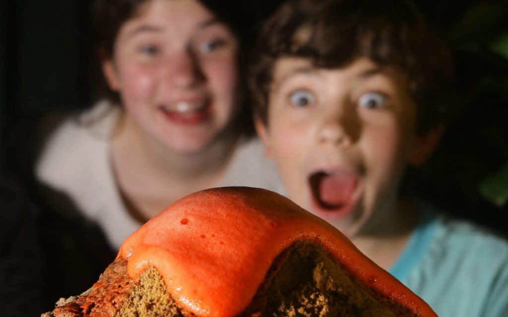 Kids looking at a model volcano