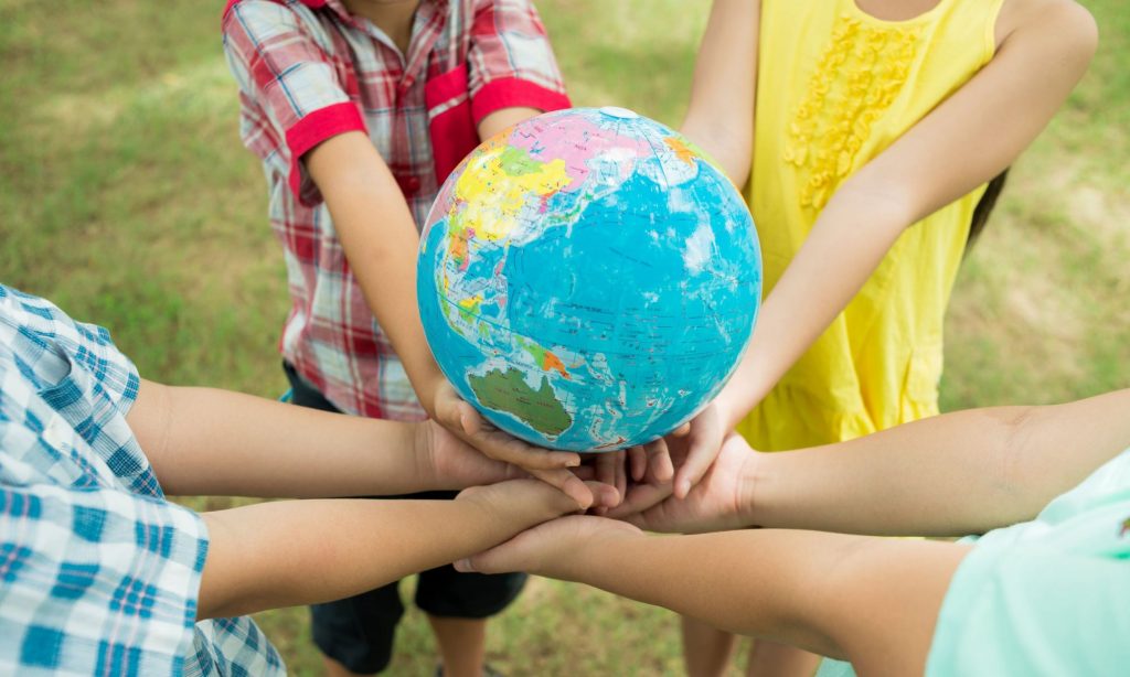 the world is in their hands; kids holding globe