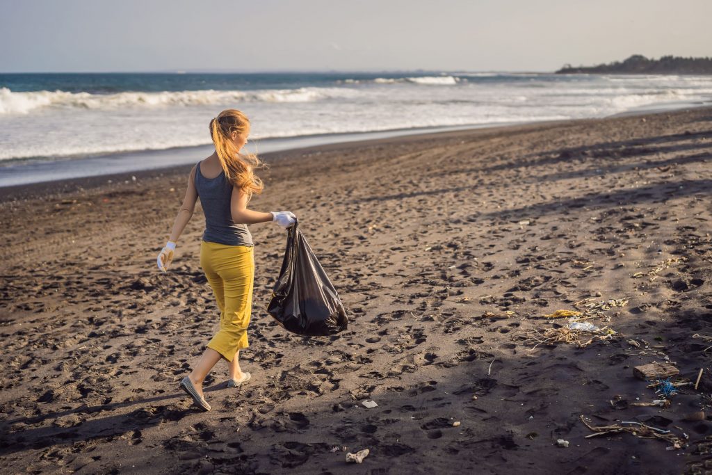 Beach clean up, Young woman cleaning up the beach